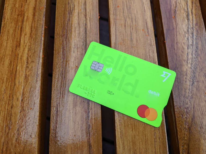 Die neon-grüne Wise Bank Karte für günstige Währungsumrechnungen, hier abgebildet auf einem dunkelbraun lackierten Holztisch.